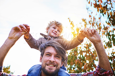 Buy stock photo Low angle shot of a handsome young man piggybacking his son outside during autumn