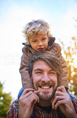 Buy stock photo Cropped portrait of a handsome young man piggybacking his son outside during autumn