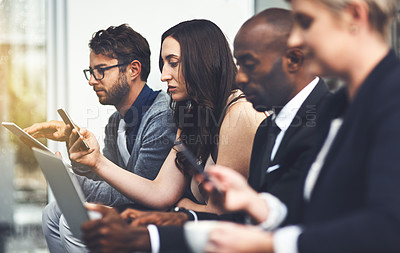 Buy stock photo Shot of a group of businesspeople using various digital devices in an office