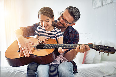 Buy stock photo Cropped shot of a handsome mature man teaching his young daughter how to play the guitar