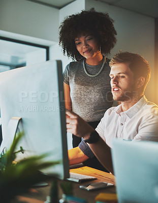 Buy stock photo Shot of two young designers working together on a computer in the office