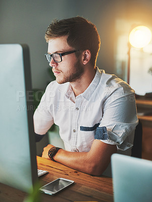 Buy stock photo Shot of a young designer working on a computer while wearing glasses in the office