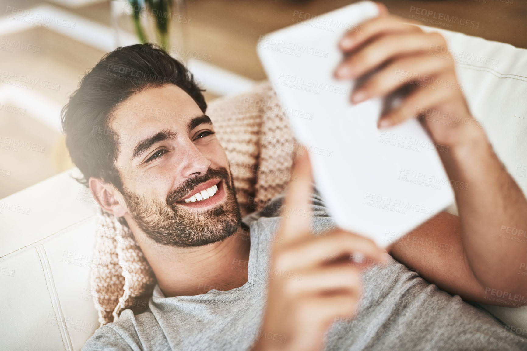 Buy stock photo Shot of a young man using wireless technology on the sofa at home