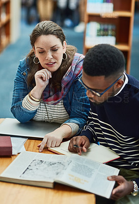 Buy stock photo Shot of two university students working together in the library at campus