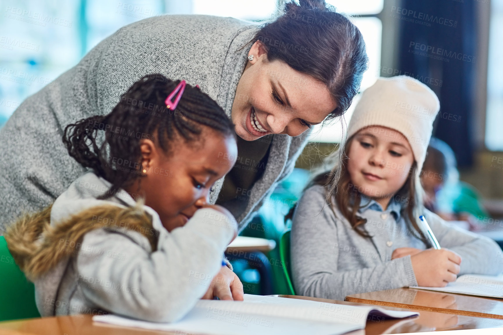 Buy stock photo Teacher, learning and help kids in class for education, study or writing knowledge in book. Children, happy woman and assistance of students in lesson for development or reading at elementary school