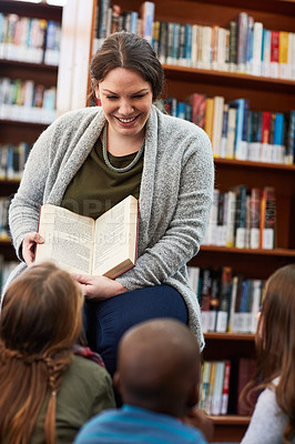 Buy stock photo Cropped shot of elementary school kids looking at a book in the library
