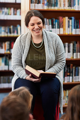 Buy stock photo Cropped shot of a female teacher reading to elementary school kids in the library