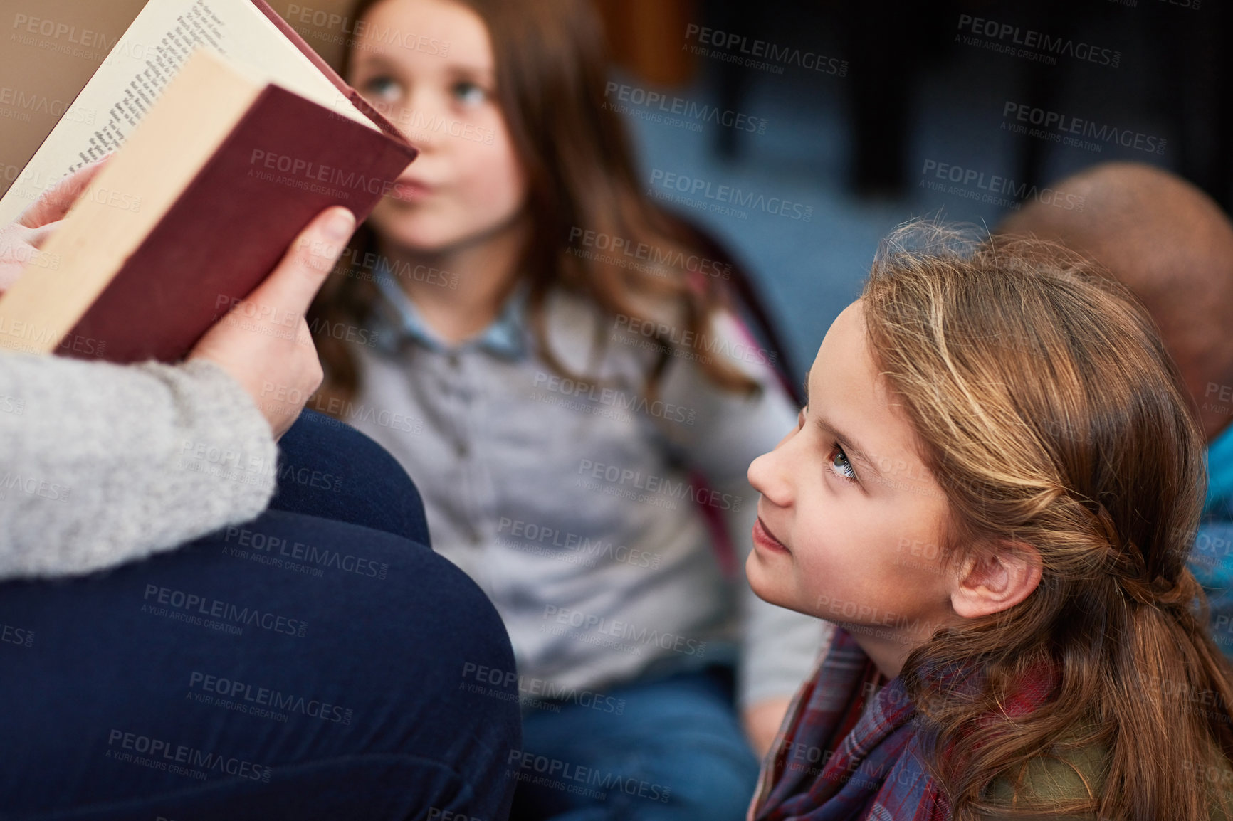 Buy stock photo Cropped shot of an unrecognizable female teacher reading to elementary school kids in the library