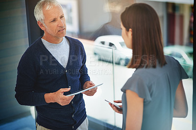 Buy stock photo High angle shot of two colleagues having a conversation in their office