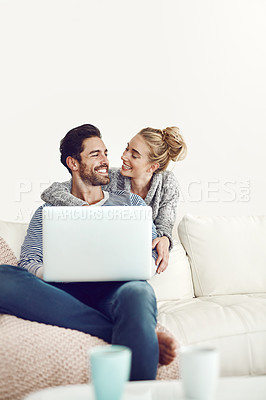 Buy stock photo Shot of a young couple using a laptop on their sofa at home