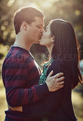 Buy stock photo Shot of an affectionate young couple kissing outdoors