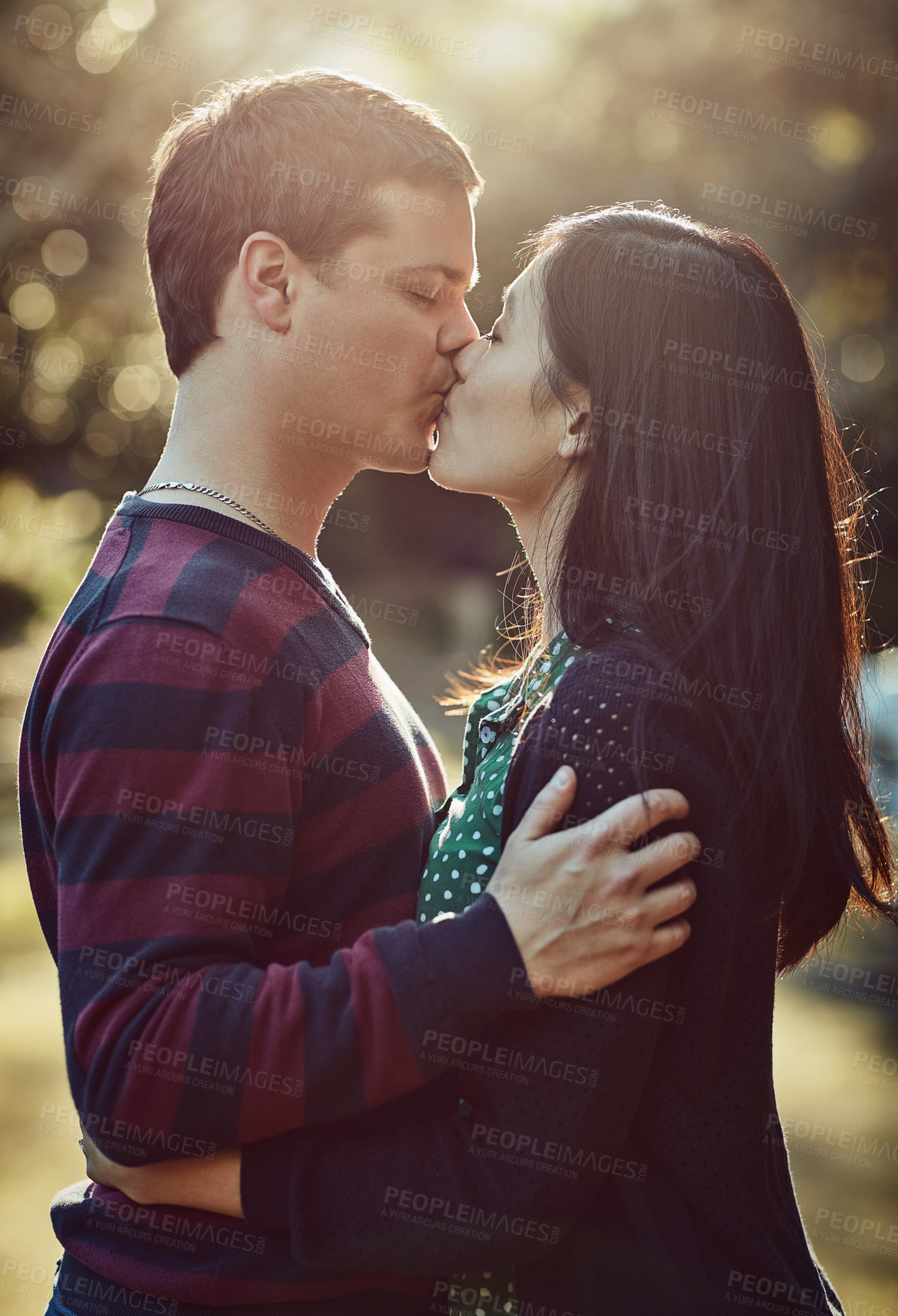 Buy stock photo Love, kiss and couple on date in park with embrace, support and trust in interracial relationship together. Nature, man and woman hug in garden for outdoor bonding, happy romance and partnership.