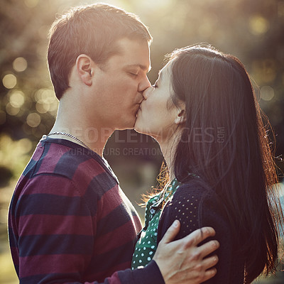 Buy stock photo Shot of an affectionate young couple kissing outdoors