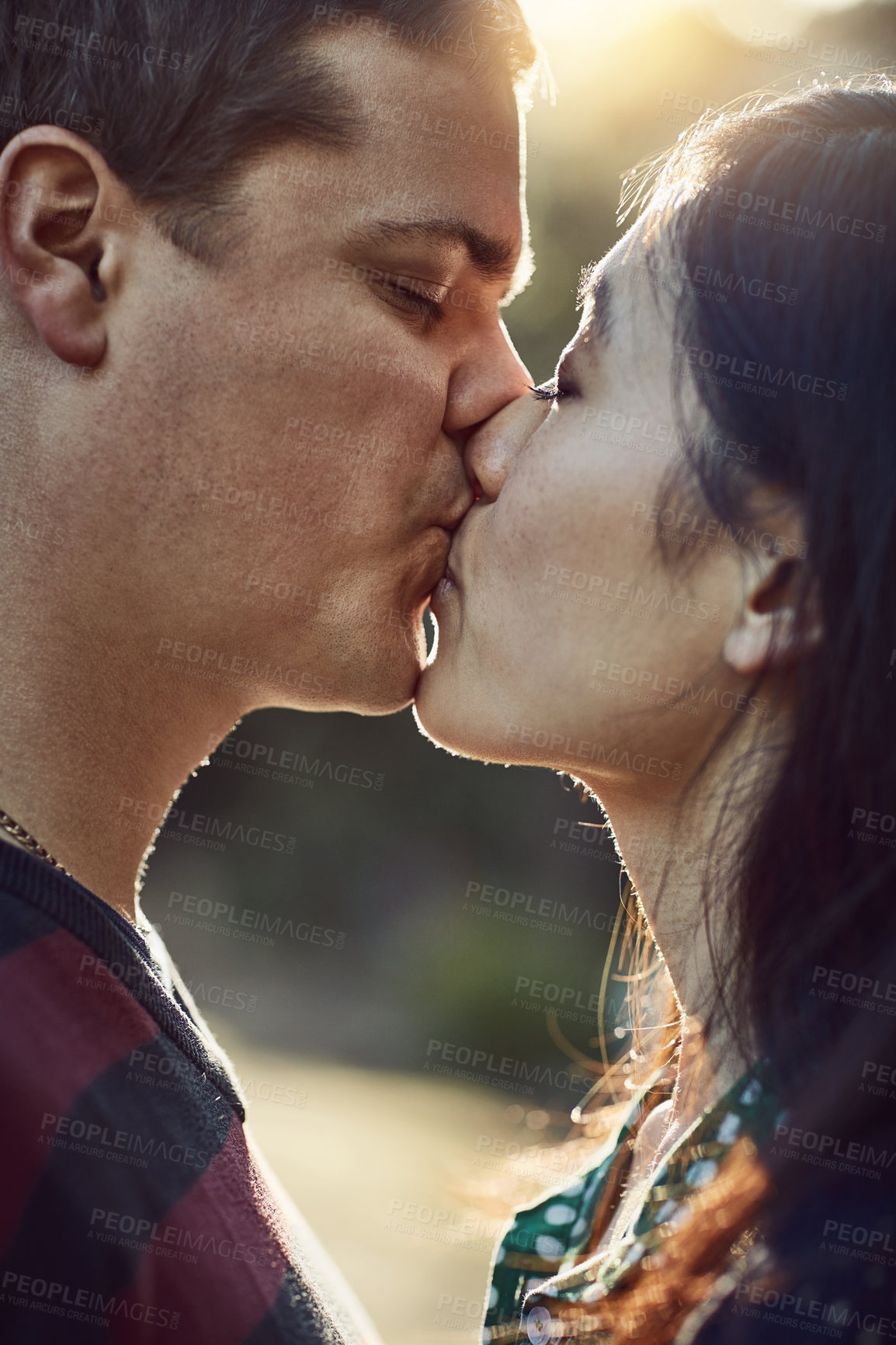 Buy stock photo Shot of an affectionate young couple kissing outdoors