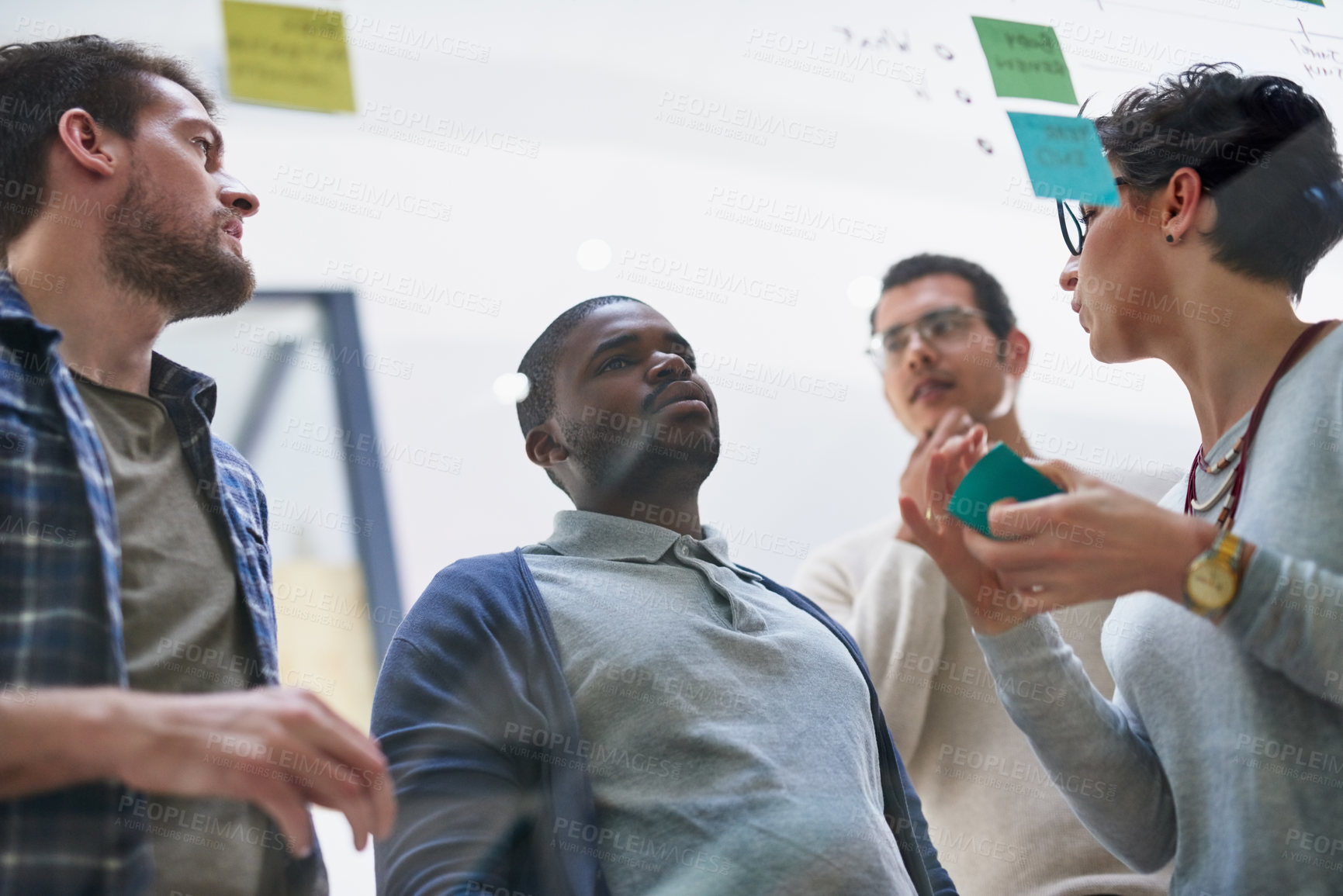 Buy stock photo Shot of a group of designers brainstorming with notes on a glass wall in an office