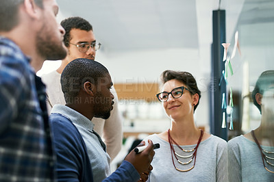 Buy stock photo Shot of a group of designers brainstorming with notes on a glass wall in an office