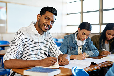 Buy stock photo Cropped portrait of a handsome young university student taking notes while sitting in class