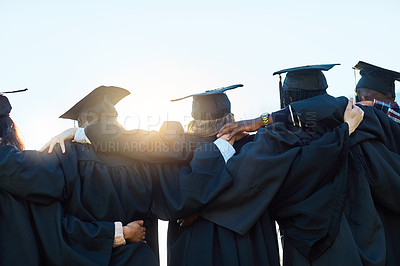 Buy stock photo Rearview shot of a group of students standing in a row on graduation day