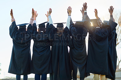 Buy stock photo Rearview shot of a group of students standing in a line with their arms raised on graduation day