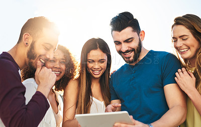 Buy stock photo Shot of young friends using a tablet outside