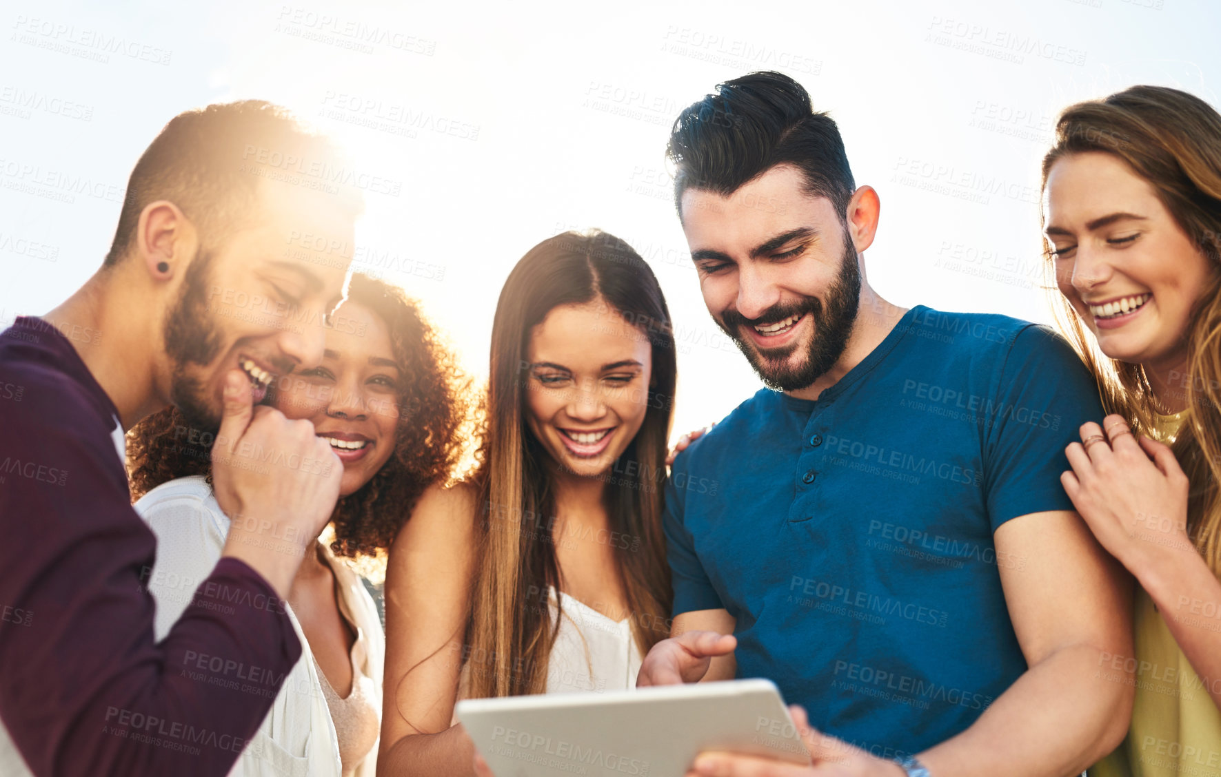 Buy stock photo Shot of young friends using a tablet outside