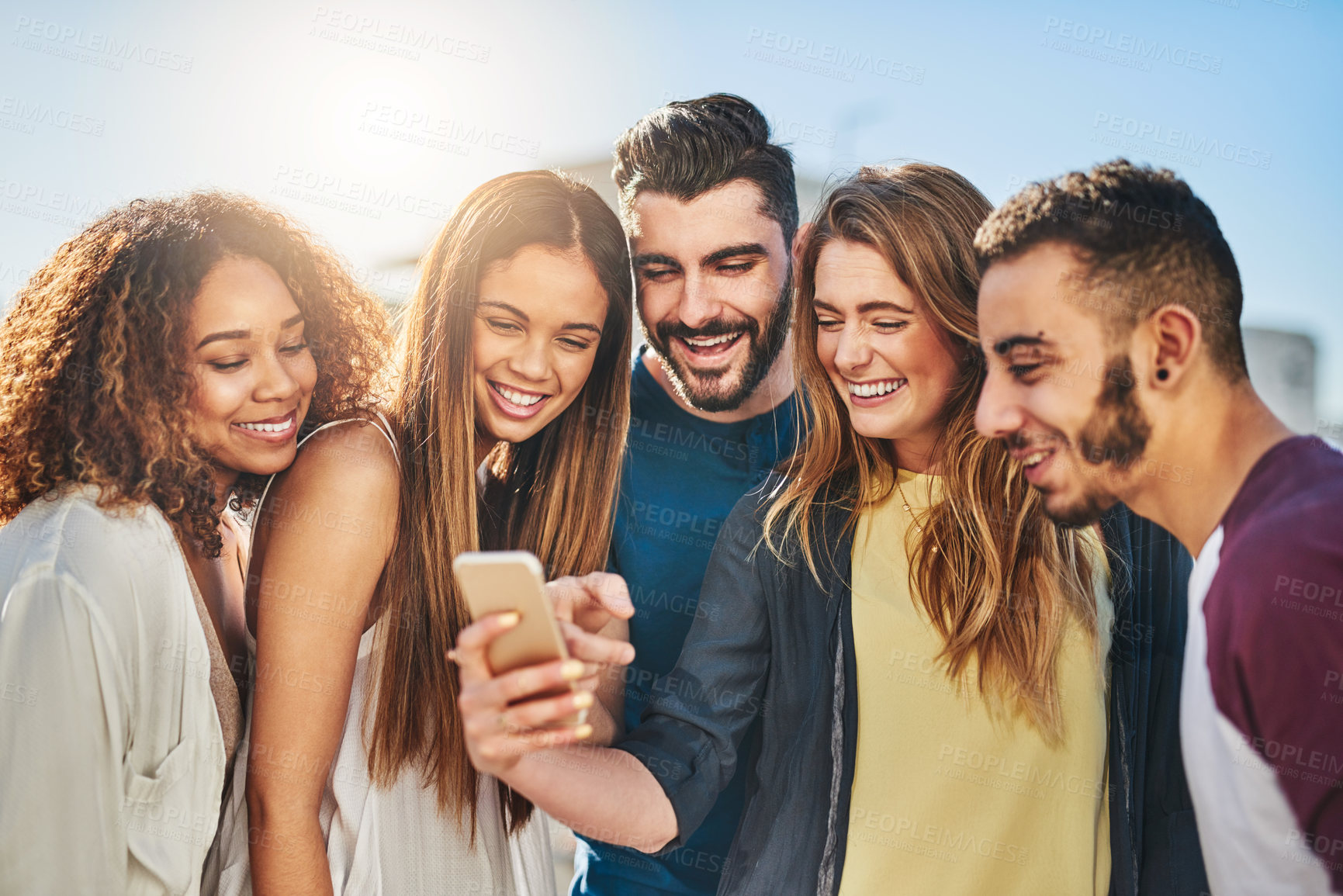 Buy stock photo Shot of young friends using a smartphone outside