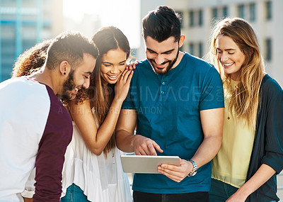 Buy stock photo Shot of young friends using a tablet outside