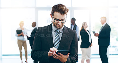 Buy stock photo Cropped shot of a handsome businessman using a tablet in the office with his colleagues in the background