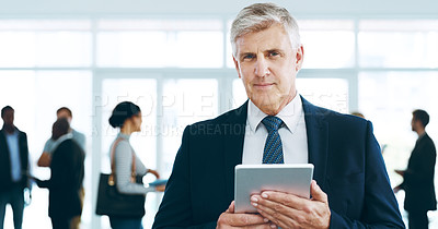 Buy stock photo Cropped portrait of a handsome mature businessman using a tablet in the office with his colleagues in the background