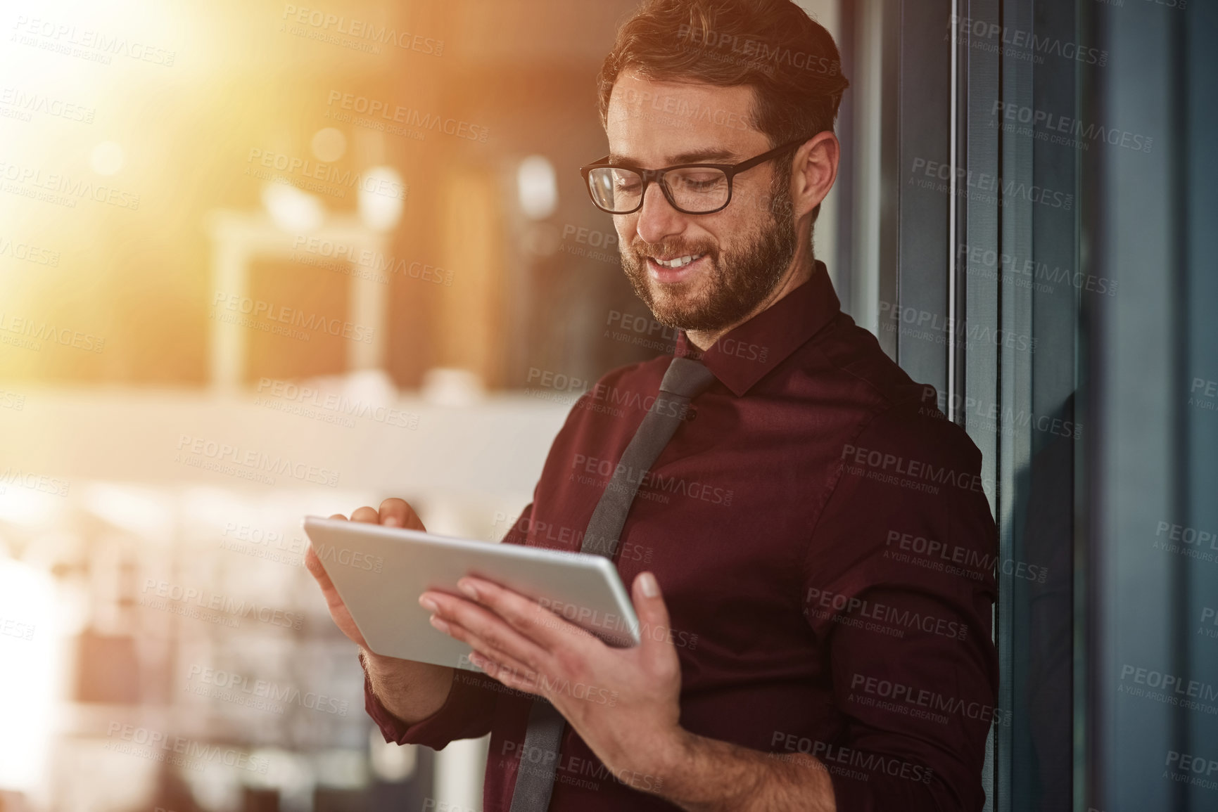 Buy stock photo Shot of a young businessman using a digital tablet in a modern office