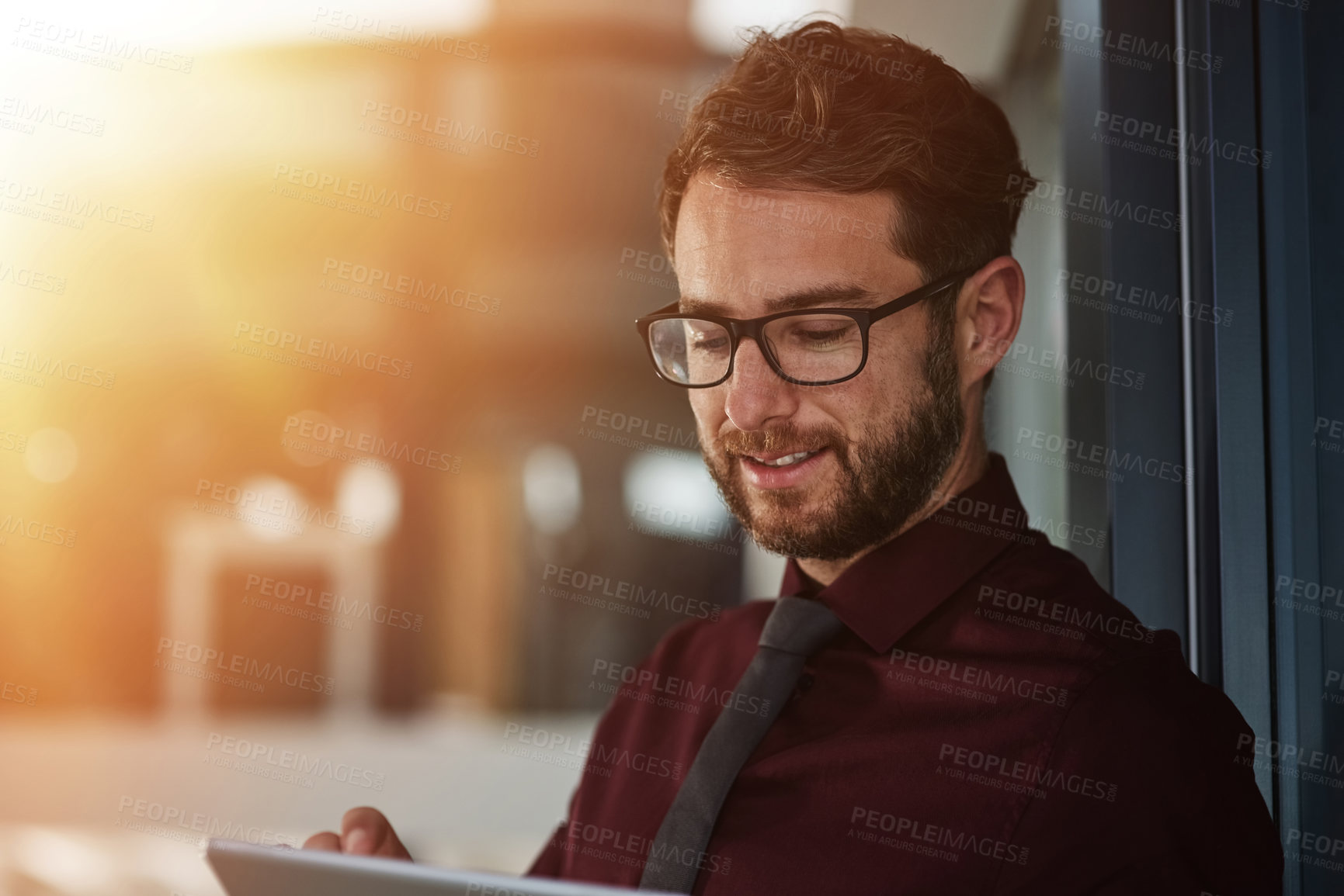 Buy stock photo Shot of a young businessman using a digital tablet in a modern office