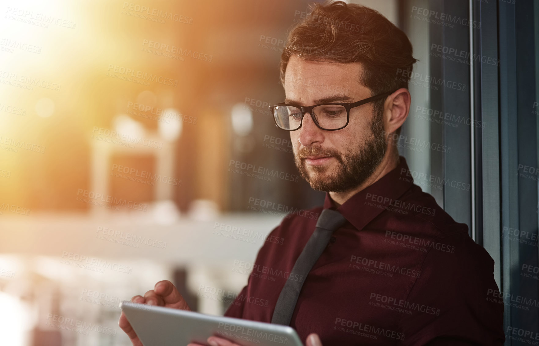 Buy stock photo Shot of a young businessman using a digital tablet in a modern office