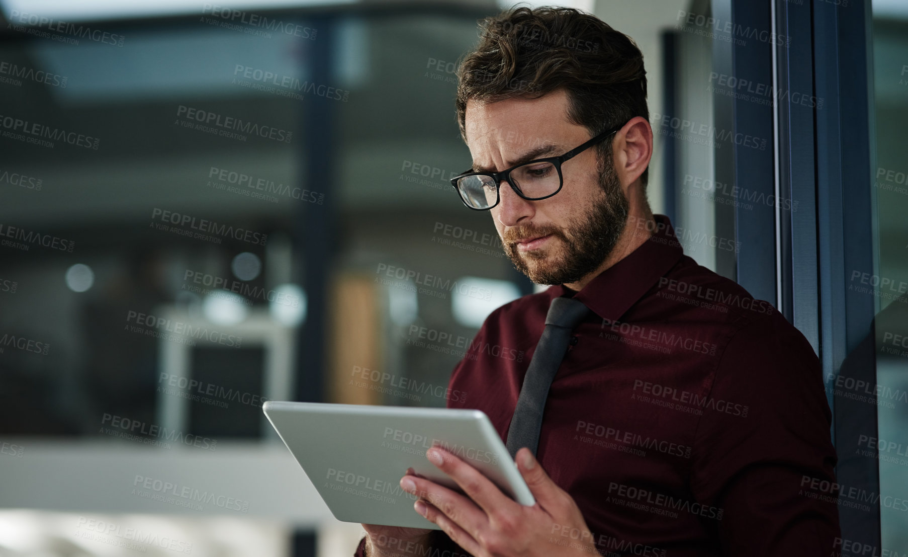 Buy stock photo Shot of a young businessman using a digital tablet in a modern office