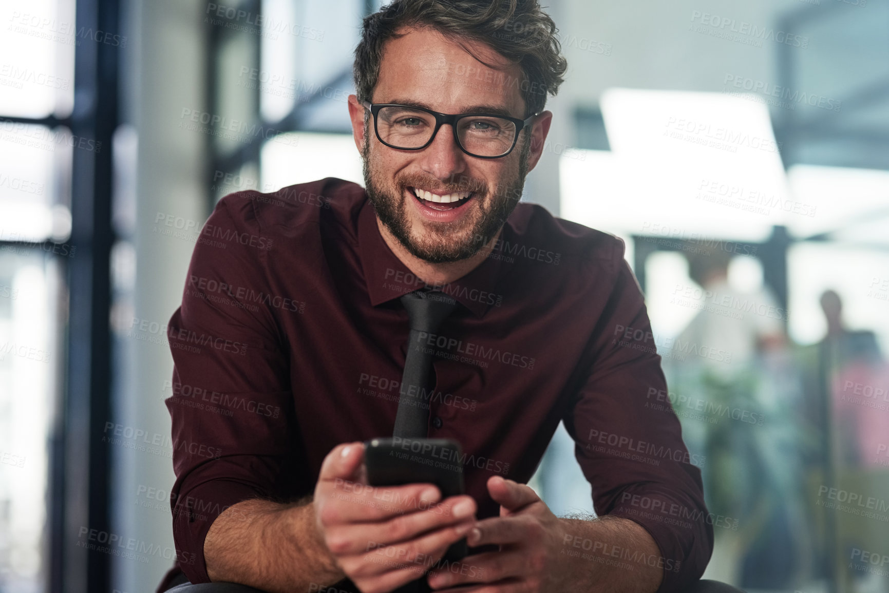 Buy stock photo Shot of a young businessman using a mobile phone in a modern office
