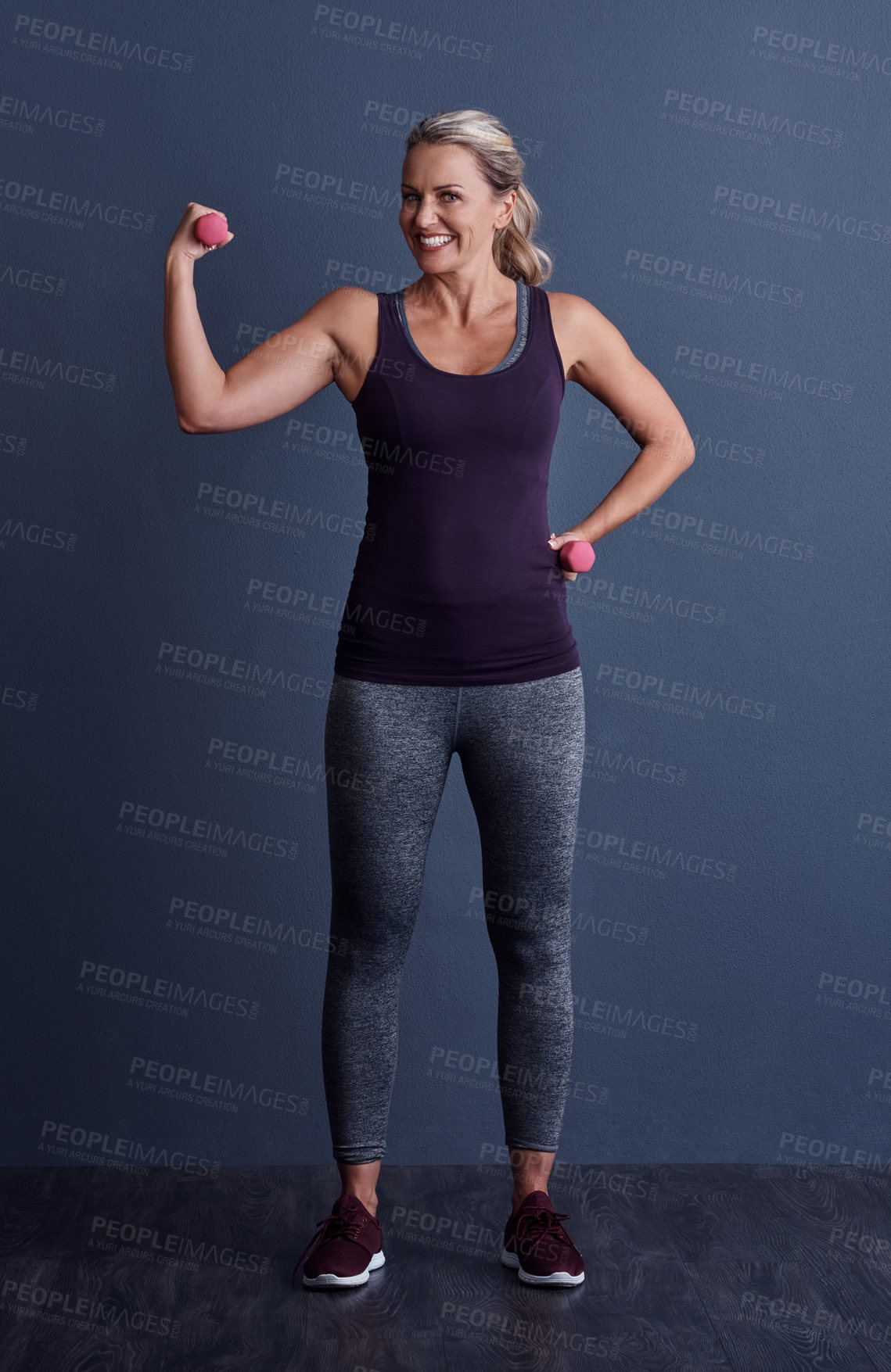Buy stock photo Studio portrait of an attractive mature woman working out with dumbbells against a blue background