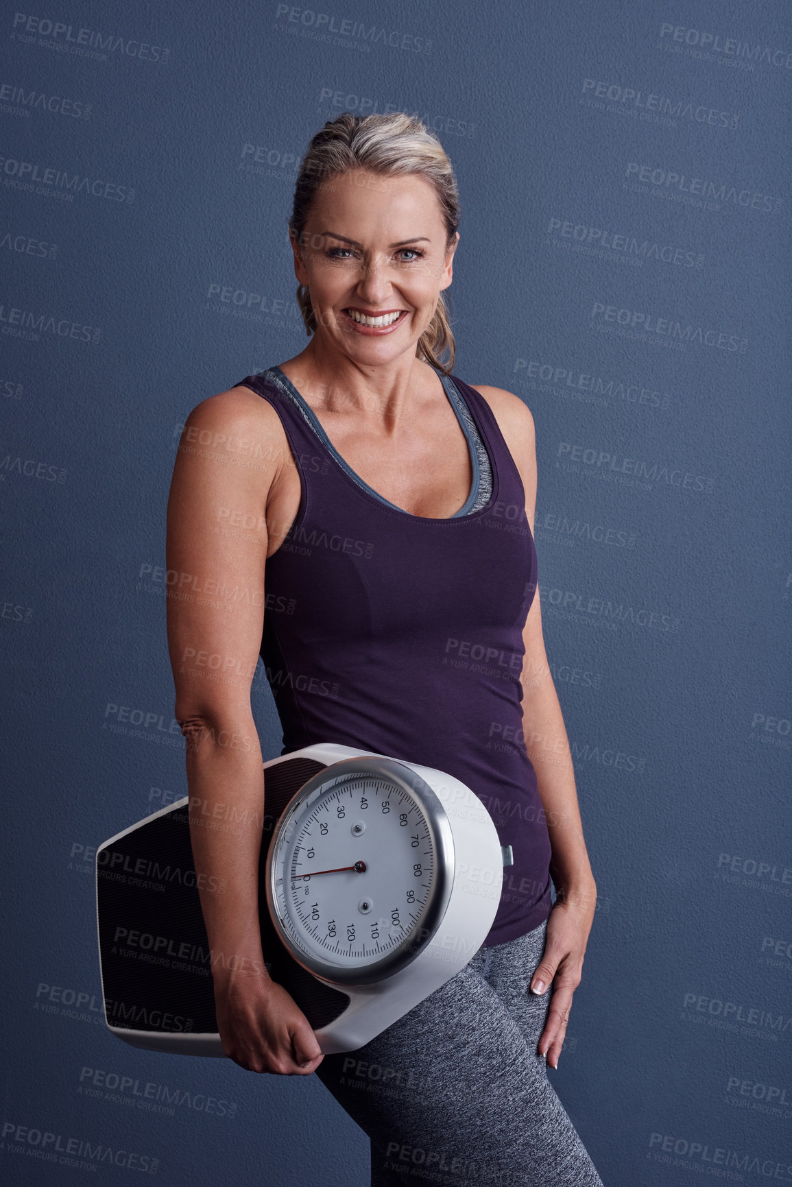 Buy stock photo Studio portrait of an attractive mature woman holding a weightscale against a blue background