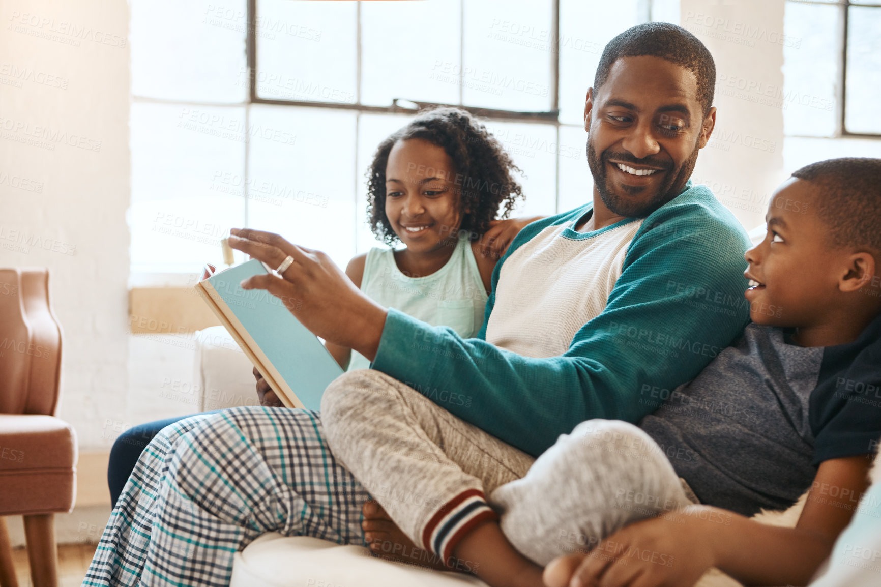 Buy stock photo Shot of a father and his children reading a book indoors