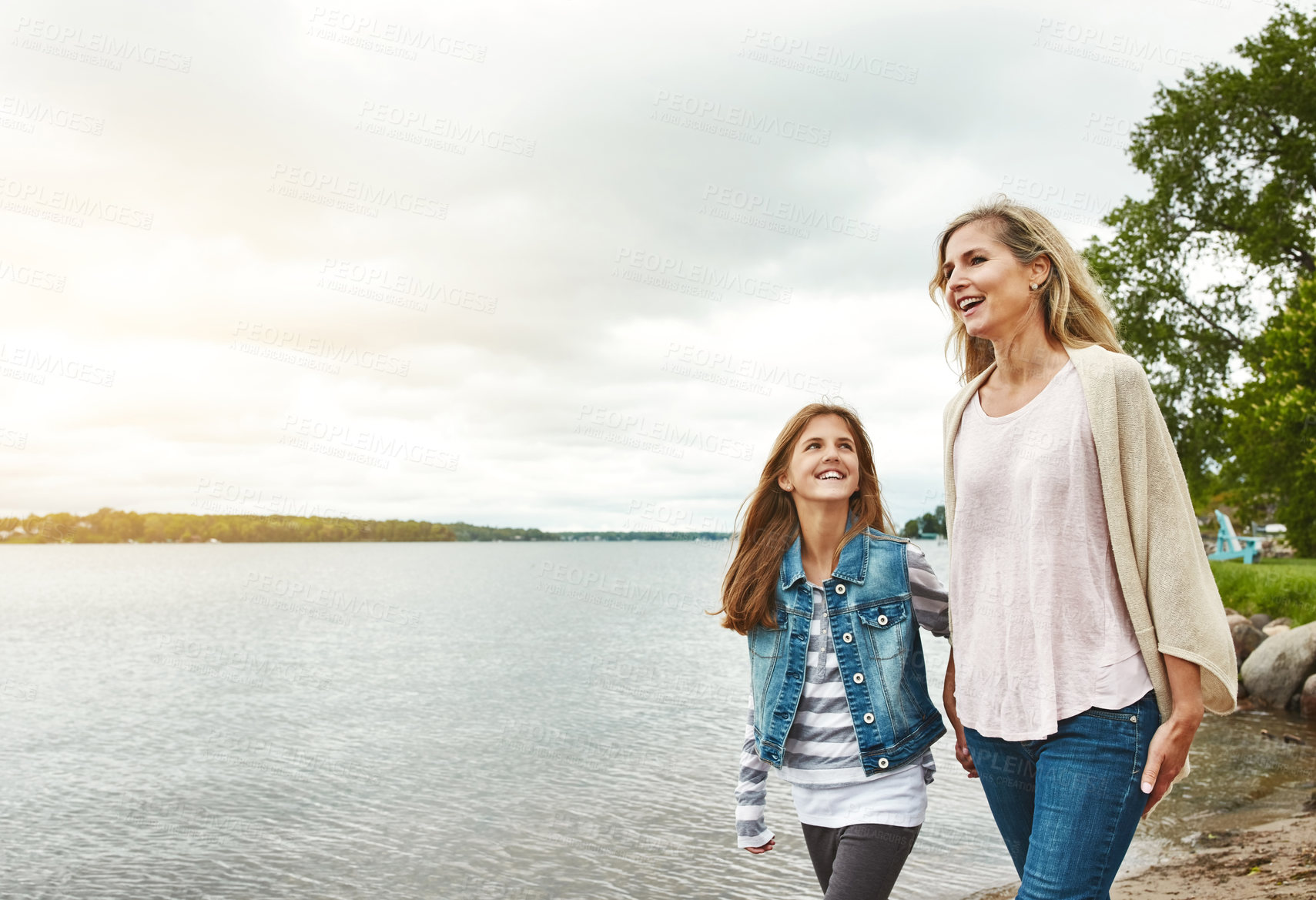 Buy stock photo Happy, mother and daughter by lake with walk, connection and bonding together outdoor on weekend break. Space, mom and child stroll by river with support, trust and scenic environment for vacation.