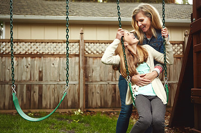 Buy stock photo Shot of a mother and her daughter playing on a swing in their backyard