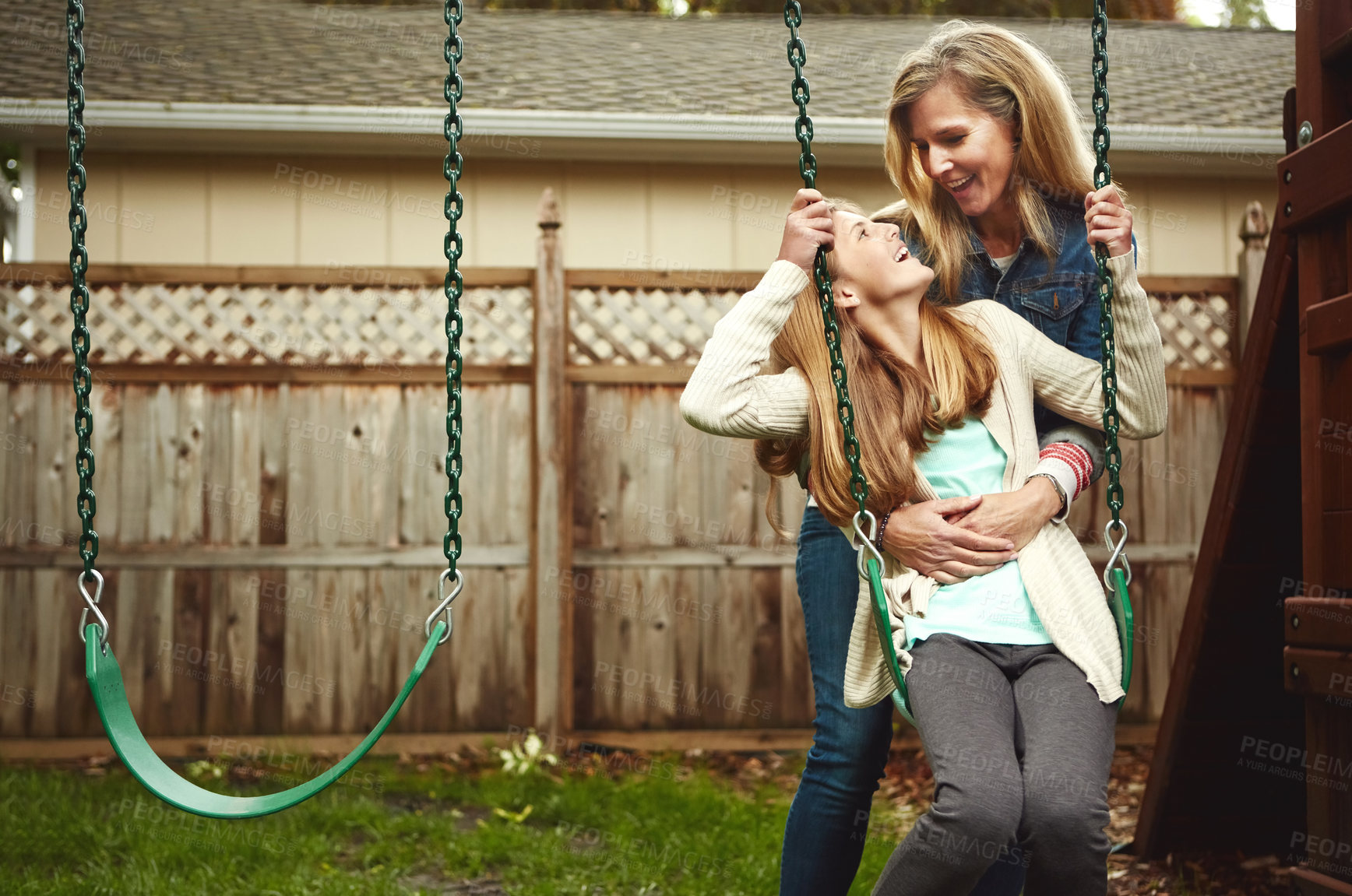 Buy stock photo Shot of a mother and her daughter playing on a swing in their backyard