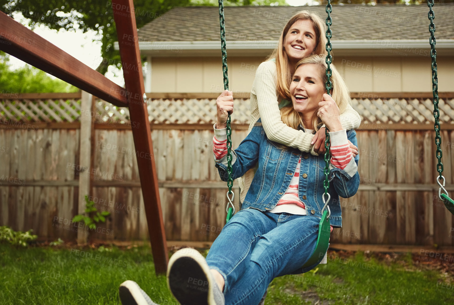 Buy stock photo Shot of a mother and her daughter playing on a swing in their backyard