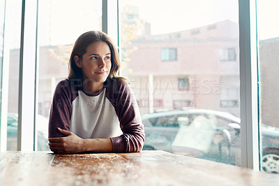 Buy stock photo Shot of an attractive young woman sitting deep in thought at a cafe