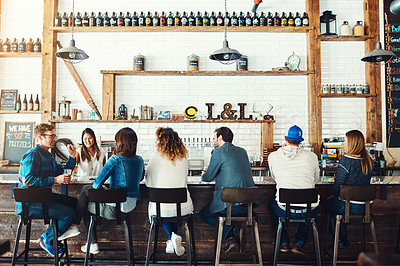 Buy stock photo Rearview shot of people drinking at a bar
