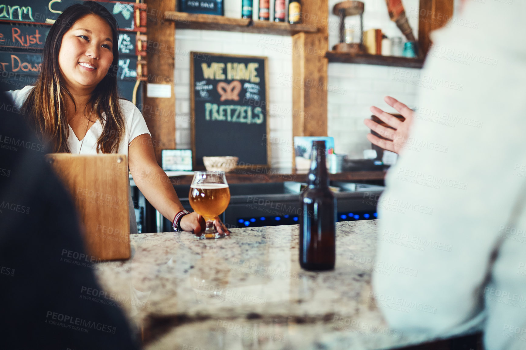 Buy stock photo Shot of a young woman serving drinks in a bar 