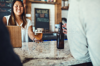 Buy stock photo Shot of a young woman serving drinks in a bar 