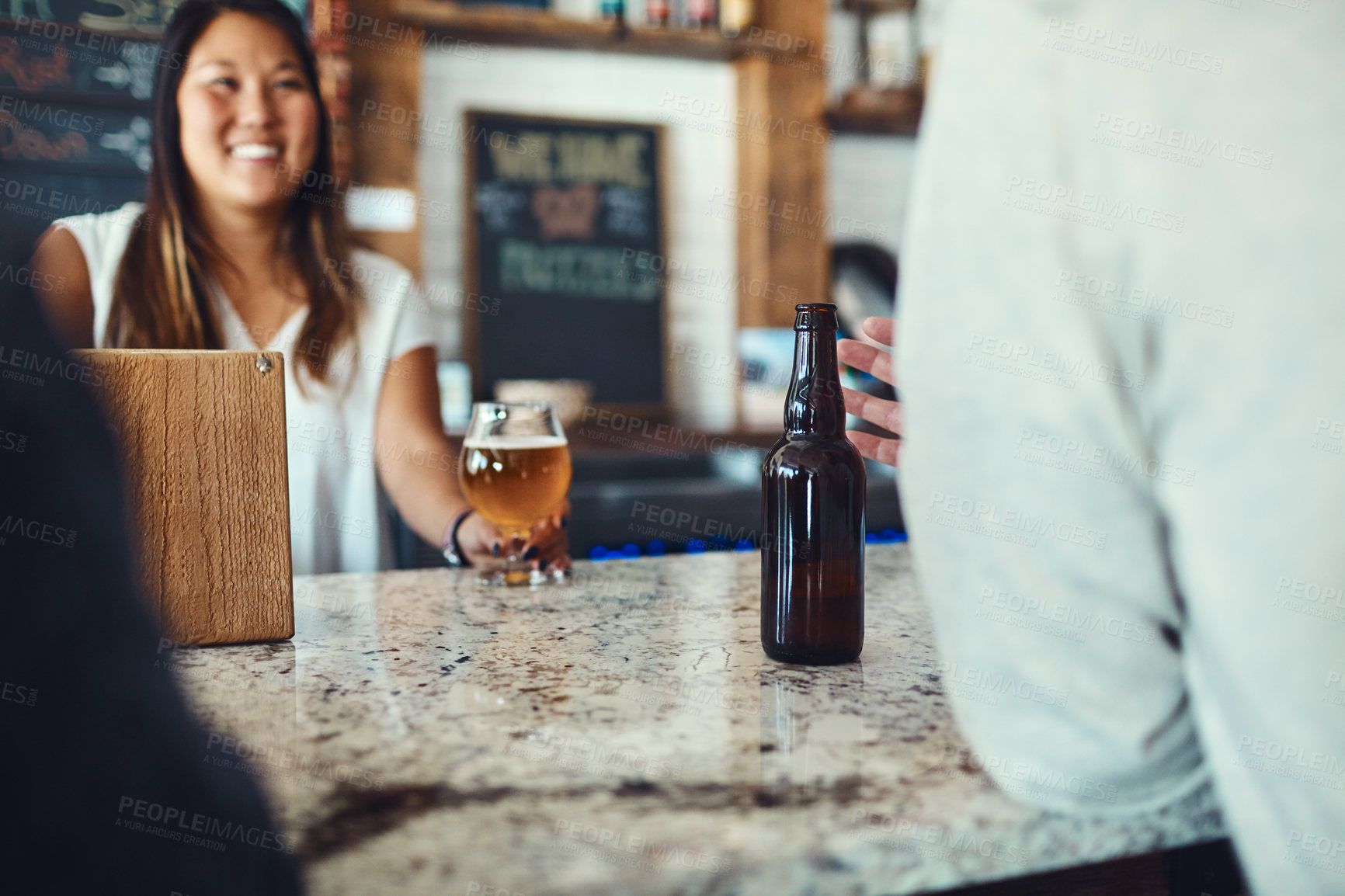 Buy stock photo Shot of a young woman serving drinks in a bar 