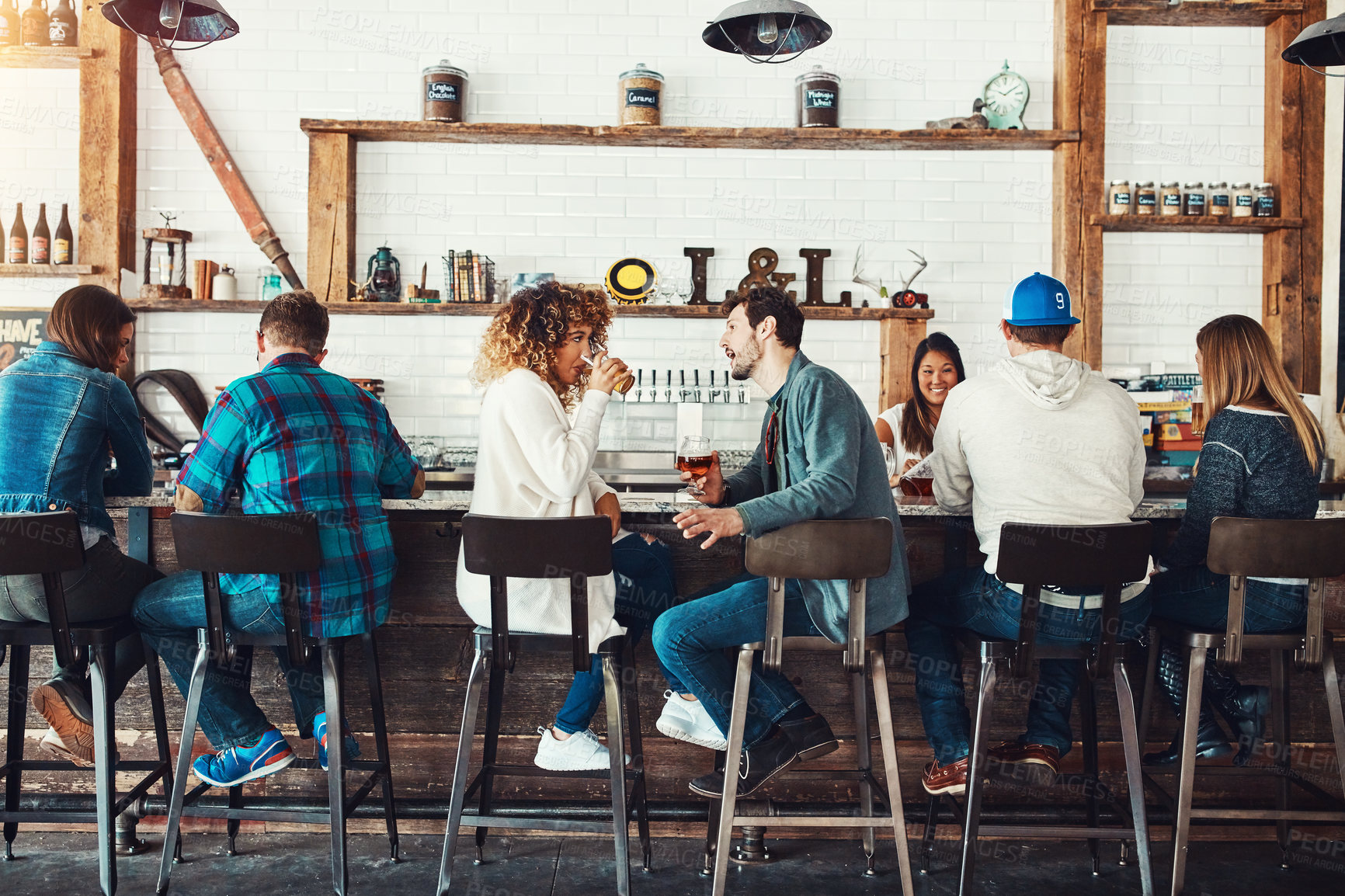 Buy stock photo Shot of young people enjoying a drink at a bar