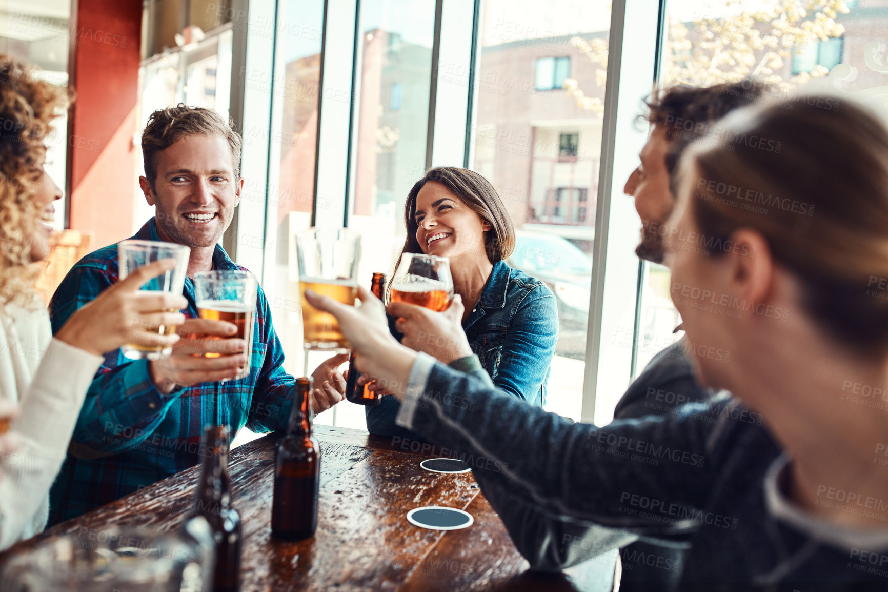 Buy stock photo Shot of a group of friends making a toast while enjoying themselves in a bar