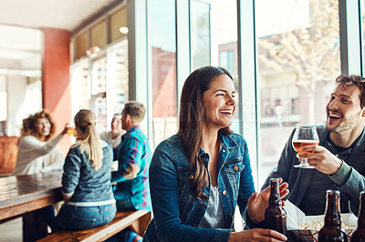 Buy stock photo Cropped shot of a young couple having drinks in a bar with people blurred in the background