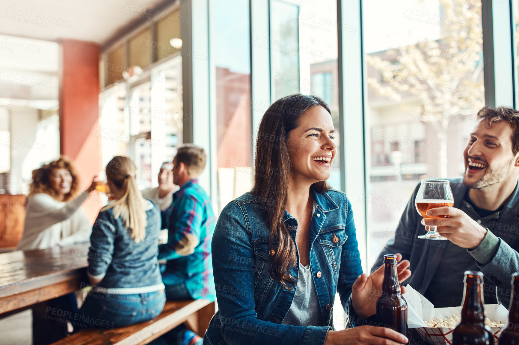 Buy stock photo Cropped shot of a young couple having drinks in a bar with people blurred in the background